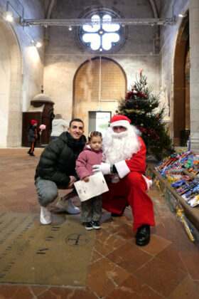 La petite Elia, accompagnée de son papa pour la distribution de jouets de Noël